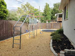 View of jungle gym featuring a fenced backyard and a trampoline
