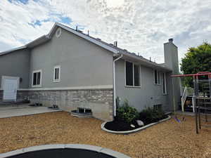View of side of home featuring brick siding, stucco siding, and a chimney