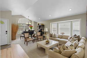 Living area featuring vaulted ceiling, a chandelier, light carpet, and recessed lighting