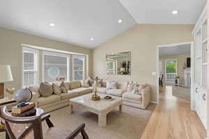 Living area with light wood-type flooring, lofted ceiling, recessed lighting, and a high end fireplace