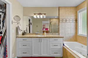 Full bathroom with a spacious closet, a shower stall, vanity, and a whirlpool tub