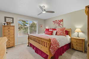 Bedroom with a textured ceiling, light carpet, and ceiling fan