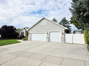 Ranch-style home with driveway, stucco siding, a garage, and a gate