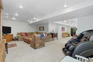 Living room with a textured ceiling, light colored carpet, and recessed lighting
