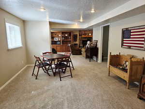 Dining area with light colored carpet, a textured ceiling, and a stone fireplace