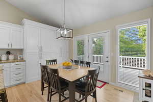 Dining area with light wood-style floors, a chandelier, and lofted ceiling