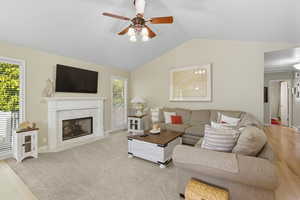 Living area featuring vaulted ceiling, a premium fireplace, and ceiling fan