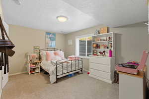 Bedroom with light carpet and a textured ceiling