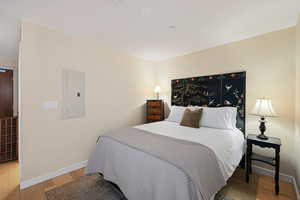 Bedroom with electric panel and light wood-style flooring