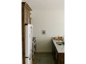 Kitchen featuring light stone countertops, dark wood finished floors, double oven range, freestanding refrigerator, and a peninsula