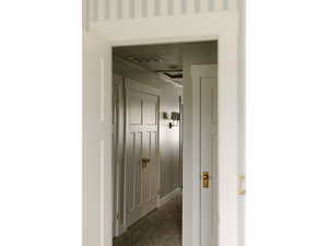 Corridor with dark colored carpet and baseboards