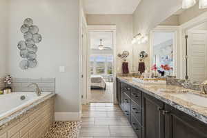 Full bath with double vanity, connected bathroom, and a bath