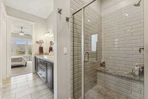 Ensuite bathroom featuring a stall shower, vanity, and ceiling fan