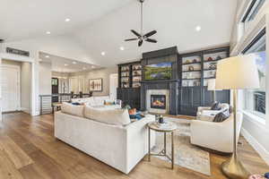 Living room featuring a high end fireplace, high vaulted ceiling, wood finished floors, ceiling fan, and a chandelier