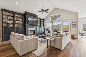 Living area with high vaulted ceiling, a high end fireplace, ceiling fan, hardwood / wood-style floors, and recessed lighting