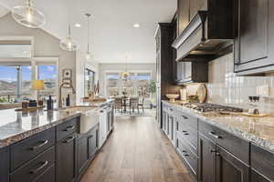 Kitchen with hanging light fixtures, light stone counters, decorative backsplash, light wood-type flooring, and recessed lighting
