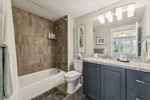 Full bathroom featuring shower / bath combination with curtain, vanity, a textured ceiling, and dark tile patterned flooring