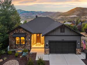 View of front of home with stone siding, board and batten siding, concrete driveway, and a garage