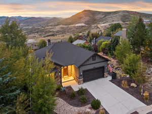 View of front of home featuring stone siding, concrete driveway, a mountain view, and an attached garage