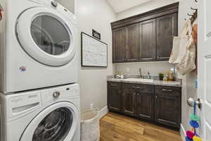 Laundry room with dark wood finished floors, stacked washer and clothes dryer, and cabinet space