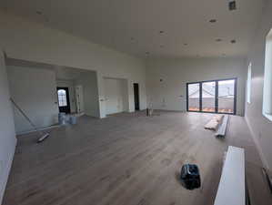 Unfurnished living room featuring a towering ceiling, wood finished floors, and recessed lighting