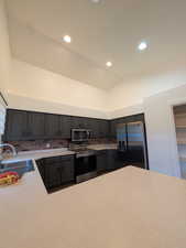 Kitchen featuring appliances with stainless steel finishes, vaulted ceiling, light countertops, recessed lighting, and tasteful backsplash