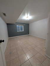 Spare room with a textured ceiling and light tile patterned flooring