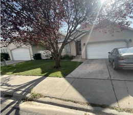 Obstructed view of property with stucco siding, driveway, a front yard, and an attached garage