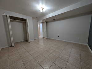 Unfurnished bedroom with a textured ceiling, a closet, and light tile patterned floors