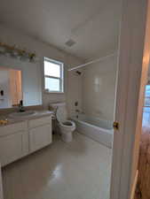 Full bath featuring vanity, washtub / shower combination, a textured ceiling, and light flooring