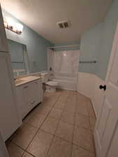 Bathroom featuring vanity, shower / tub combination, a textured ceiling, a wainscoted wall, and light tile patterned floors