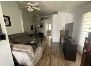 Living area featuring wood finished floors, lofted ceiling, and ceiling fan