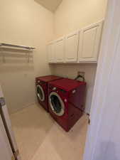 Laundry area with light floors, washer and dryer, and cabinet space