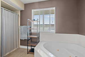 Full bath featuring light tile patterned flooring, a jetted tub, and a shower stall