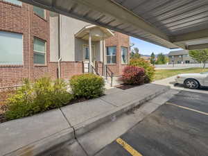 View of exterior entry with brick siding and uncovered parking