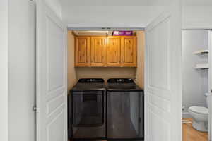 Washroom featuring cabinet space, independent washer and dryer, and wood finished floors