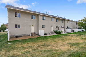 Rear view of house with a yard, a patio, stucco siding, and entry steps