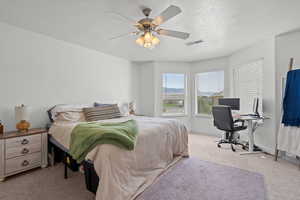 Bedroom featuring light carpet, a desk, a textured ceiling, and ceiling fan