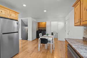 Kitchen featuring stainless steel appliances, washing machine and clothes dryer, light wood-style floors, dark countertops, and recessed lighting