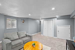 Carpeted living room featuring recessed lighting and a textured ceiling