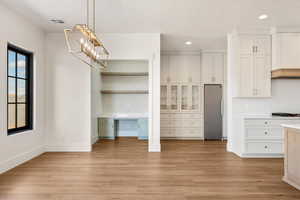 Unfurnished dining area featuring built in desk, light wood-style floors, recessed lighting, a chandelier, and a textured ceiling