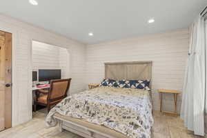 Bedroom featuring wooden walls, an office area, and recessed lighting