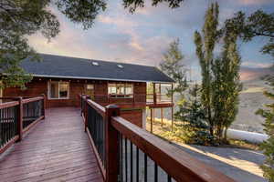 Back of property with a shingled roof and a wooden deck