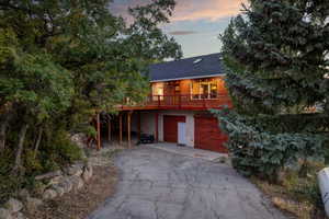 Rustic home featuring driveway, an attached garage, and roof with shingles