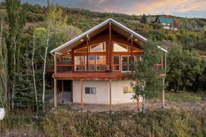 Rear view of house featuring a wooden deck and a wooded view