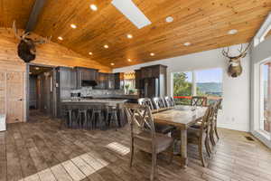 Dining space with a skylight, dark wood-type flooring, recessed lighting, a wooden ceiling with exposed beams, and a mountain view