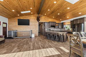 Living area with a skylight, light wood finished floors, wood walls, and wood ceiling