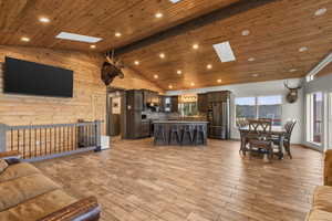 Living room with a skylight, a wood ceiling with exposed beams, light wood-type flooring, recessed lighting, and high vaulted ceiling