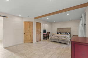 Bedroom with a barn door, recessed lighting, wooden walls, a desk, and beamed ceiling