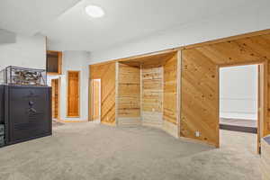 Additional living space with light carpet and wood walls